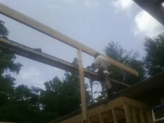 Carpenter setting a ridge beam over a new addition frame — Ice Dam Removal by Roofing Brothers in Muskegon