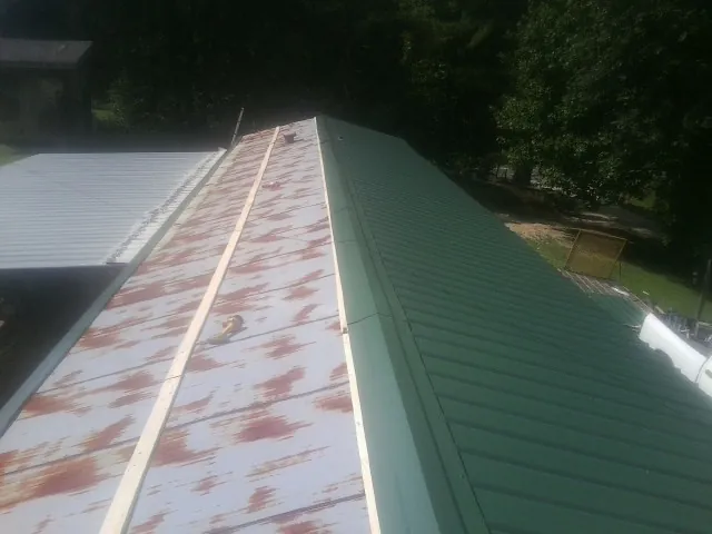 Old rusted panels beside newly installed green metal roofing — Wind Damage Roof Repair by Roofing Brothers in Muskegon