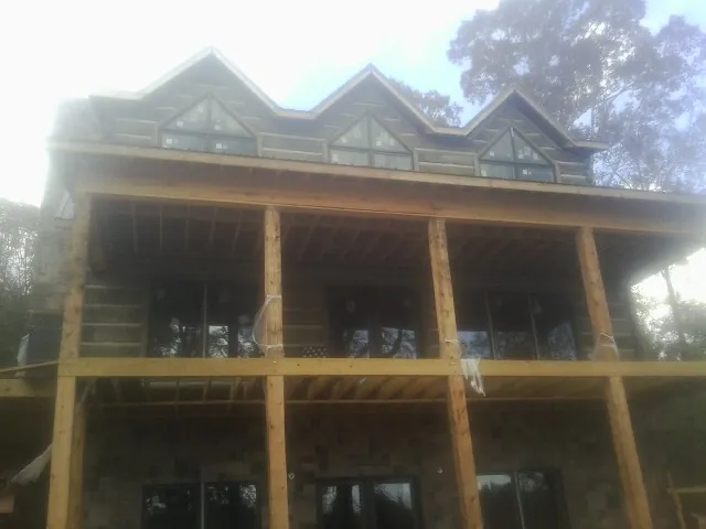 Dormers and porch framing on a large log home under construction — Roof Coating work by our crew in Muskegon