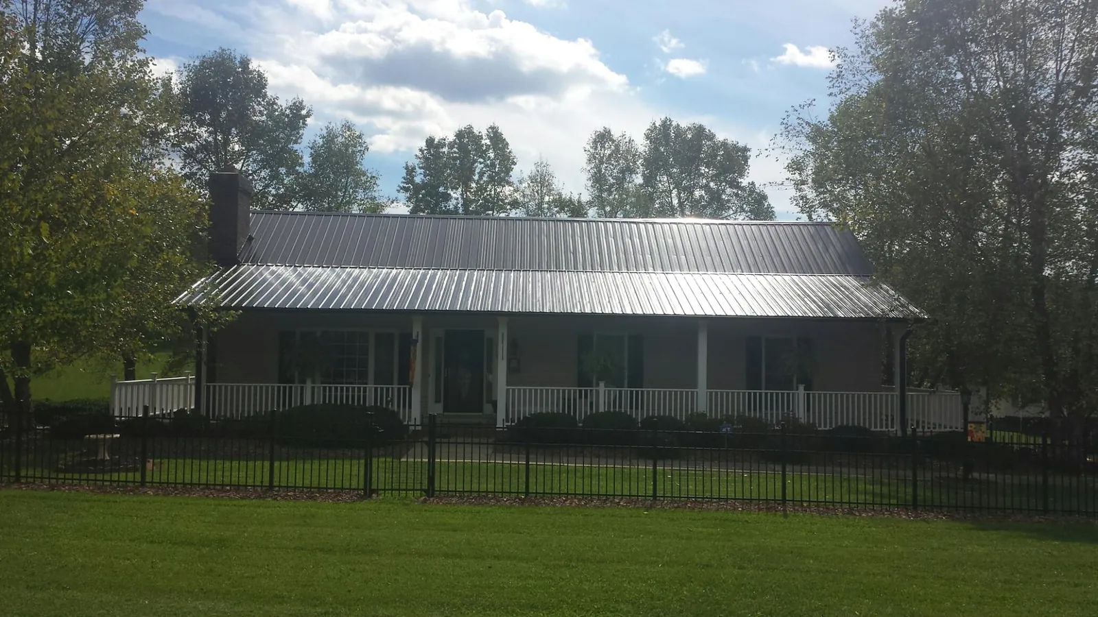 Gray metal roof on a brick ranch with a full width front porch — Gutter Guard Installation work by our crew in Muskegon