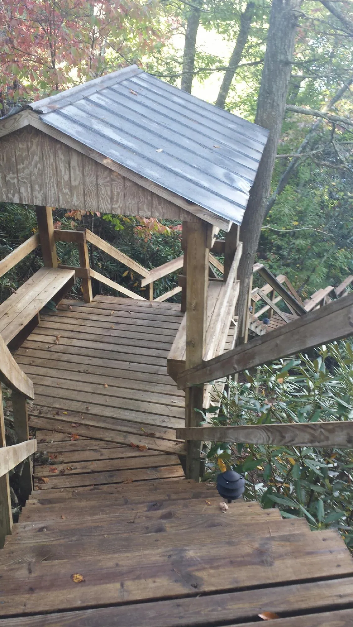 Metal roofed shelter over wooden steps on a wooded walkway — Skylight Repair & Installation work by our crew in Muskegon
