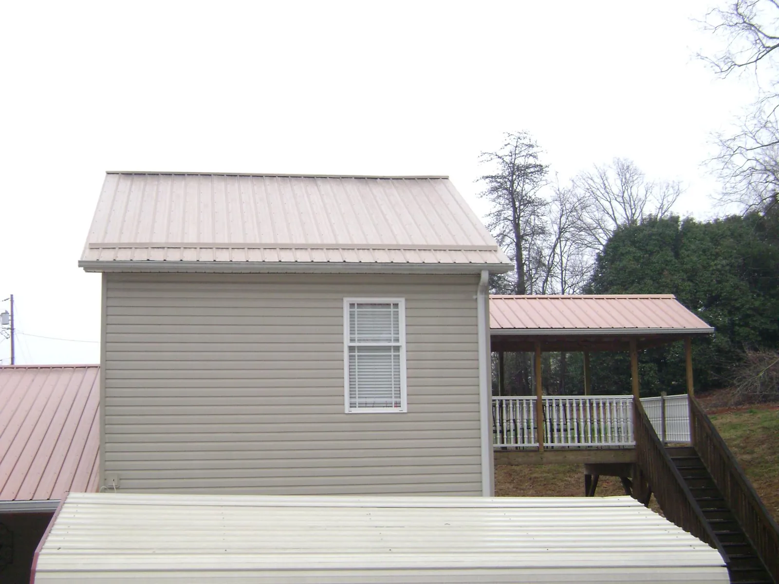 Tan metal roofs on a two story addition and attached porch in Muskegon